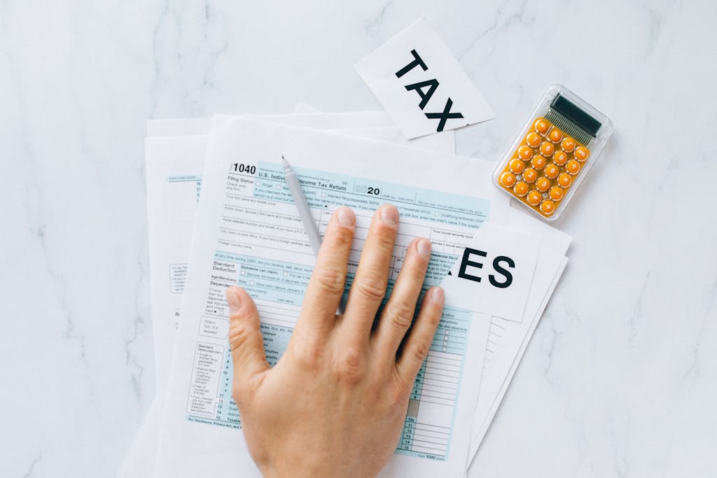 US TAX RETURN GUIDE: Close-up of a hand on tax form 1040 with a calculator on a desk.