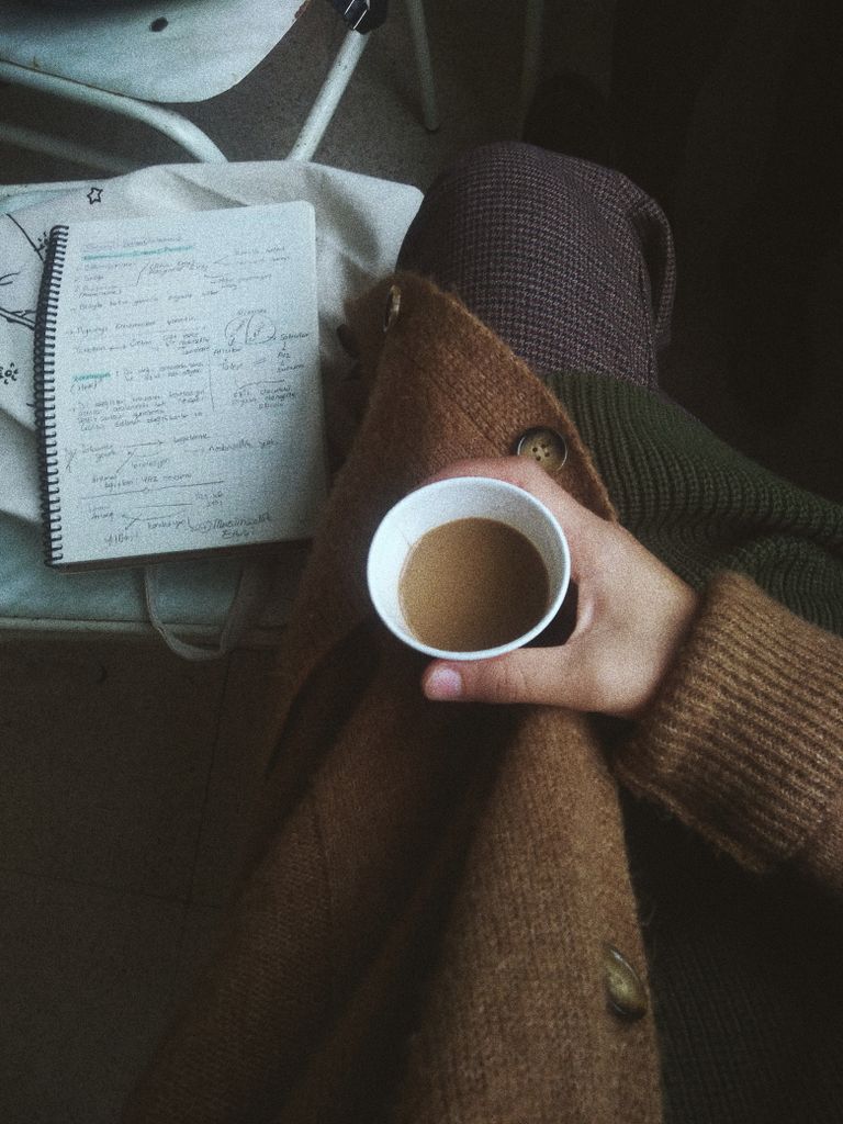 US E2 Visa Change of Status: My Honest Experience Switching Jobs on an L1 Visa 3 US visa sponsorship: A warm scene with a hand holding coffee, wearing a knitted sweater, near a notebook.